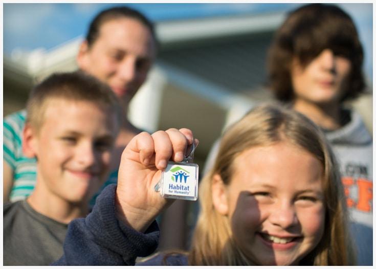 Habitat for Humanity family with keys in front of their house